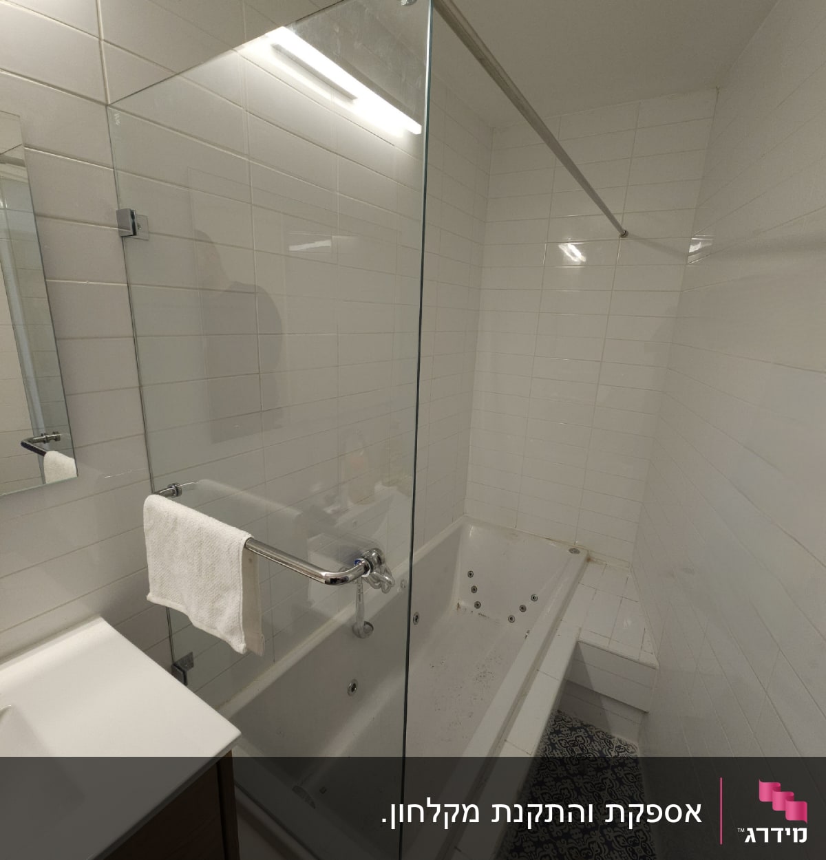 אמבטיה עם דלת זכוכית ומגבת תלויה